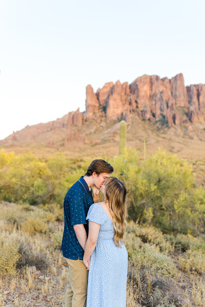 man and woman kissing in front of arizona mountain