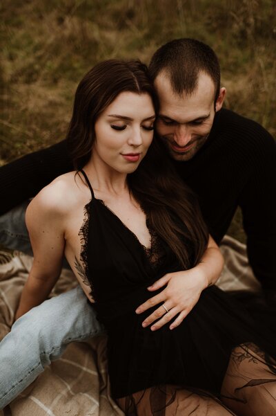 pregnant couple snuggling with eyes closed
