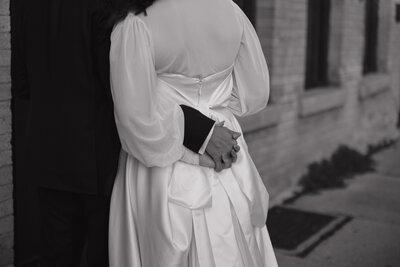 An editorial-inspired wedding scene, where the bride and groom’s tender hand-holding moment embodies effortless elegance at a high-end Wisconsin venue.