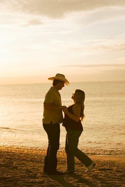 engaged couple posing infront of a lake sitting down on the ground