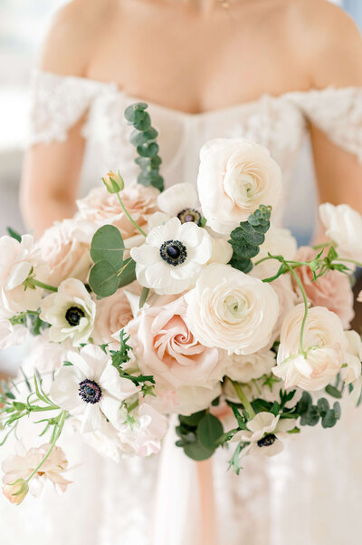 close up of a bride holding a flower bouquet with soft pinks and greens