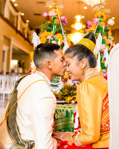 Groom kisses the bride on the nose during a Buddhist wedding at La Bella Vista.