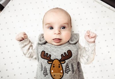 A newborn baby in an outfit with a moose on the front