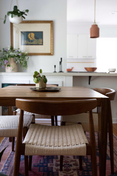 Close up of dining room table and chairs featuring woven seat cushions representing an example of art deco boho interior design.