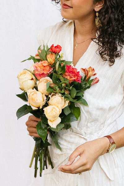 Victoria Barclay, photographer at Through Victoria's Lens, holding a vibrant bouquet