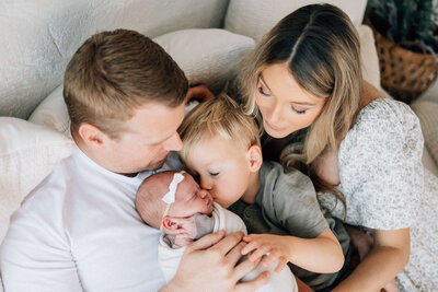 father holding newborn baby while mother hugs them