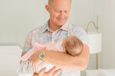 Orlando newborn photographer captures father standing in his newborn daughters room holding her and admiring her sweet innocence.