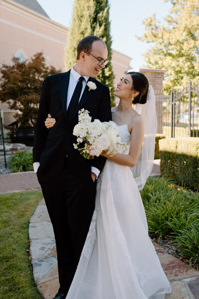 A bride and groom looking at each other with smiles.