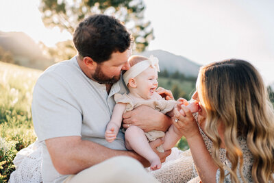parents kissing while holding their son and daughter on dad's shoulders