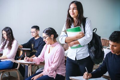 An Indigenous post-secondary student holding books in class