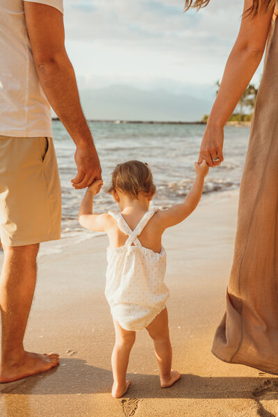 Maui Elopement Photographer captures baby walking through sand holding parents hands