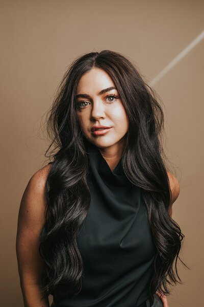 Denver boudoir photographer in her boudoir studio in Denver wearing a black top and long dark, wavy hair