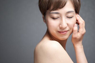 woman with clear skin, eyes closed, hand brushing face