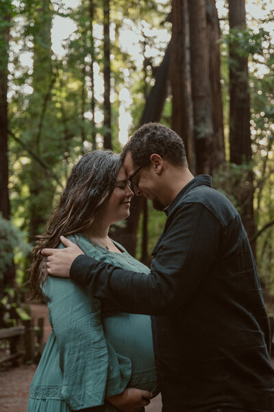 couple embracing with redwood forest in the background