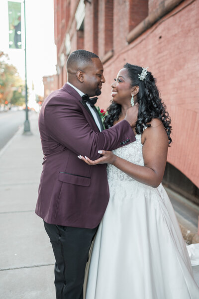 A newlywed couple about to kiss as they stand on a city sidewalk