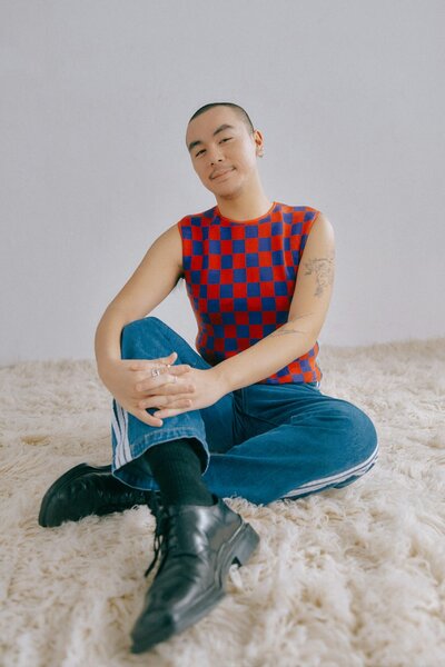 A yound asian gay man sitting on a fur rug