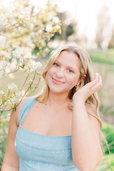 a senior posed sitting in an orange flower field with her hand in her hair in clarkston washington