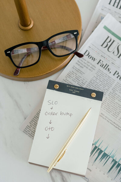 Notebook, pen, glasses and a newspaper laying on a marble table