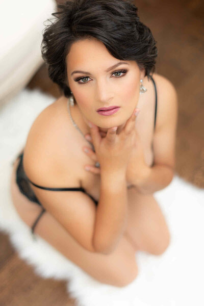 Woman in black lingerie laying on her back looking at the camera