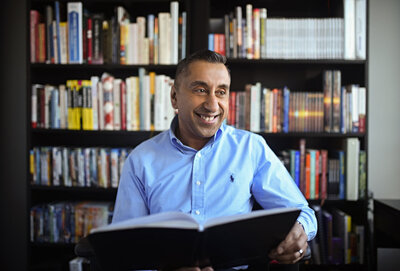 man in blue dress shirt looking off camera holding a book