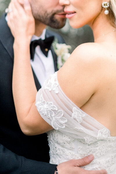 A romantic close-up of a bride and groom sharing an intimate moment at a high-end California wedding, showcasing the intricate details of the bride’s gown and jewelry, captured by Tiffany Longeway Photography.