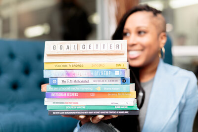 Woman in business holding stack of books