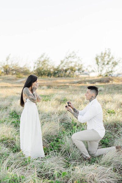 man is one knee as he pops the question to his partner
