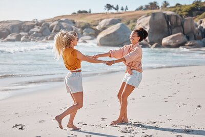 Two girls holding hands and spinning together on the beach