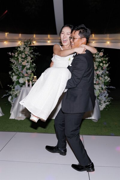 A person holding up their partner as they dance and laugh 