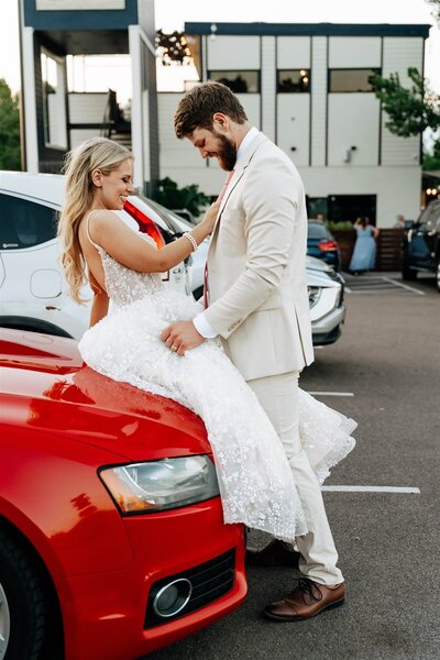 bride and groom flirting on red sports car wedding mountain crust event venue denver