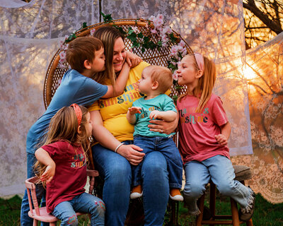 Mom sitting wiht her four children smiling at them.