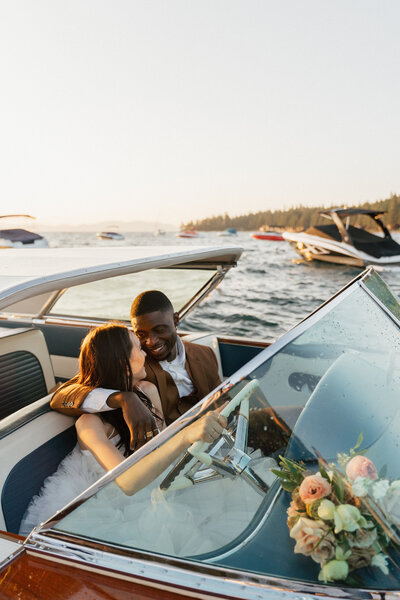 bride and groom sitting in a classic car while smiling at each other