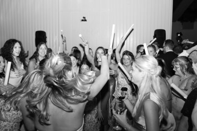 Bride celebrating and dancing with glow sticks on her wedding day in Columbus, Ohio, surrounded by friends and a lively atmosphere.