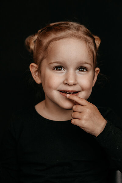 portret van een meisje met haar vinger bij haar mond
