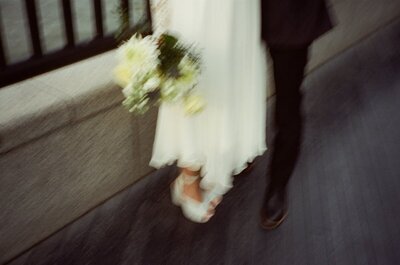 A 35mm film photo close up of a bride's shoes, bouquet, and dress, with motion blur, shot on Cinestill 400D film.