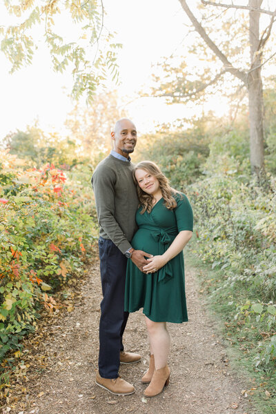 expecting couple stands in walking path during golden hour milwaukee wisconsin