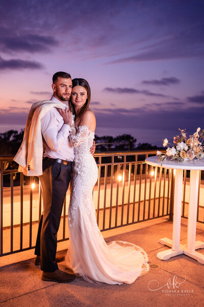 photo of bride and groom standing on a balcony at sunset taken by Palm Springs desert wedding photographer