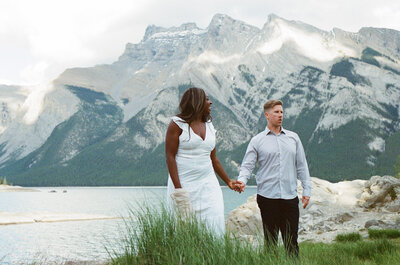 bride leads groom along rocky lake shore in Banff