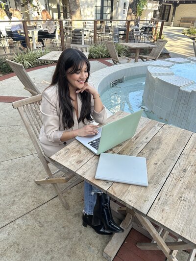 Latina web designer sitting at a coffee shop working on laptop 