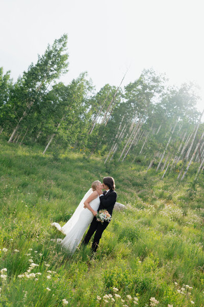 Bride and groom walking through forest after mountain wedding in Colorado