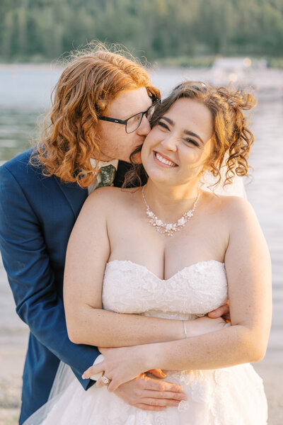 Groom kissing bride’s cheek during mountain elopement