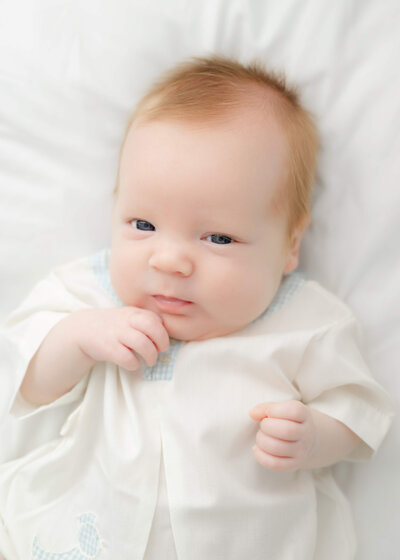 Baby boy, dressed in white and laying on white beanbag in Atlanta Newborn Photography session