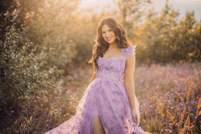 woman with long dark hair wearing a white dress while smiling at camera