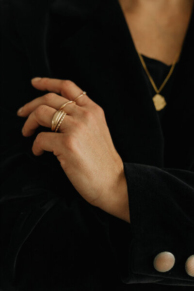detail levé ruky s prstýnky na černém kostýmku