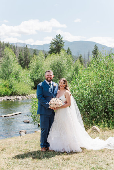 denver photographer with man and woman holdin ghands togegther for their outdoor engagement session in the mountains as they walk together on a large dirt path with the rockies int he distance