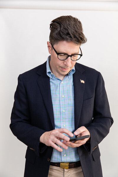 informal professional headshot of man in shirt and jacket working on his phone by laure photography
