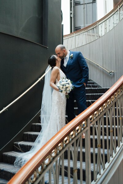 Bride and groom kiss on stairs