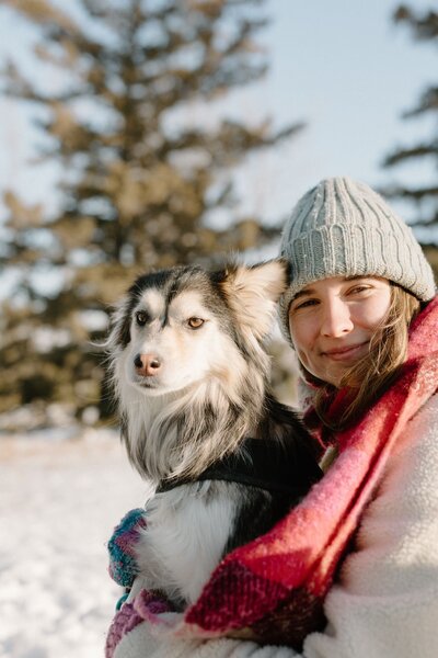 Hannah with her dog outside in the snow, embracing the beauty of winter in a heartfelt outdoor portrait.
