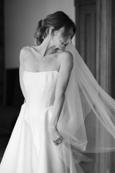 bride posing in wedding dress by window