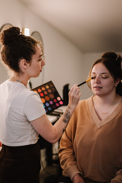 A photo of a female make up artist working on putting makeup on a client. 